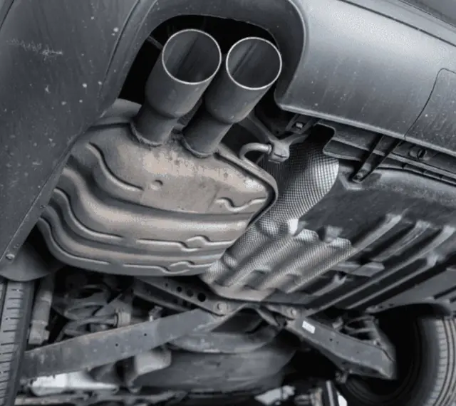The underside of a car shows a dual exhaust system leading to a large muffler, which is a key component for reducing engine noise.