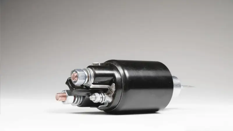 A black starter solenoid with copper and silver bolts, ready to power up an engine.