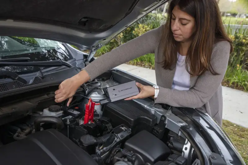 Woman connects a jump starter to a car battery. She's learning how to reset my jump starter.